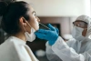 A healthcare in PPE taking nasal specimen from a woman A healthcare in PPE taking nasal specimen from a woman